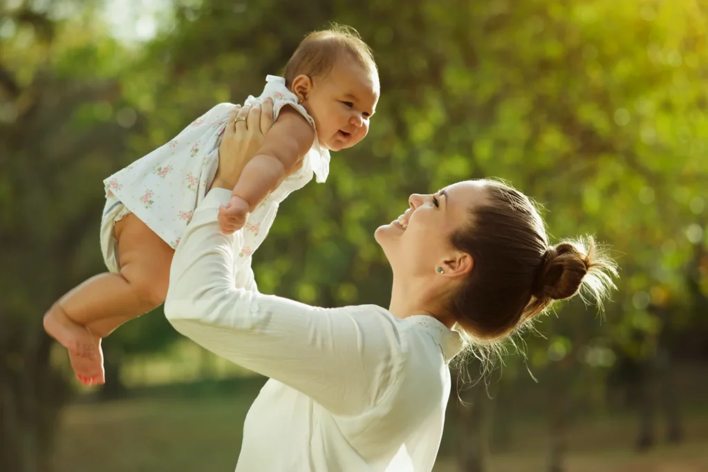 loving mother lifts happy infant outdoors